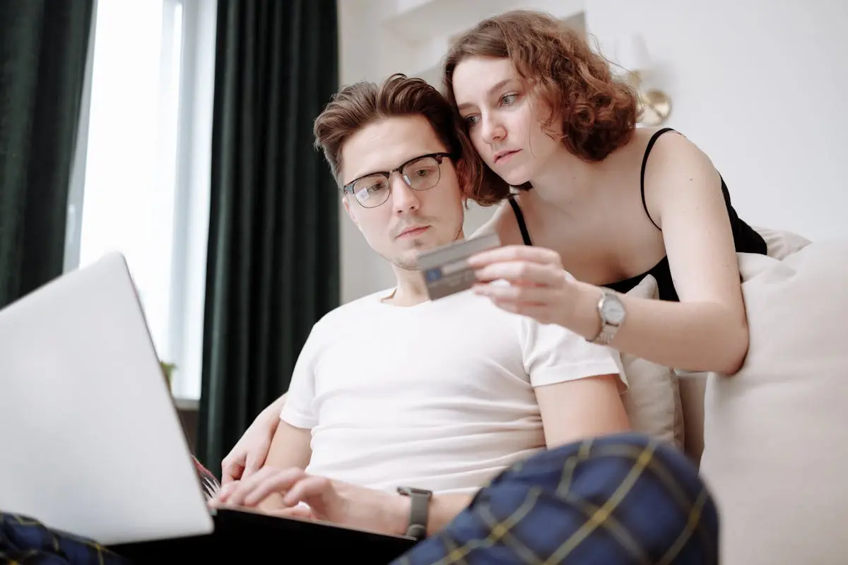 Homem e mulher no laptop, segurando cartão de crédito