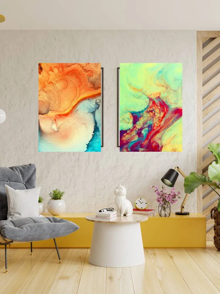 Quadros coloridos e com personalidade em uma sala de estar com poltrona cinza, móvel na cor mostarda e mesa de centro branca com itens decorativos.