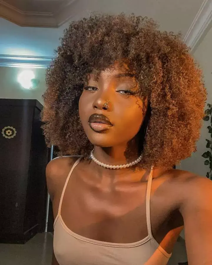 Mulher com corte de cabelo médio crespo franja assimétrica