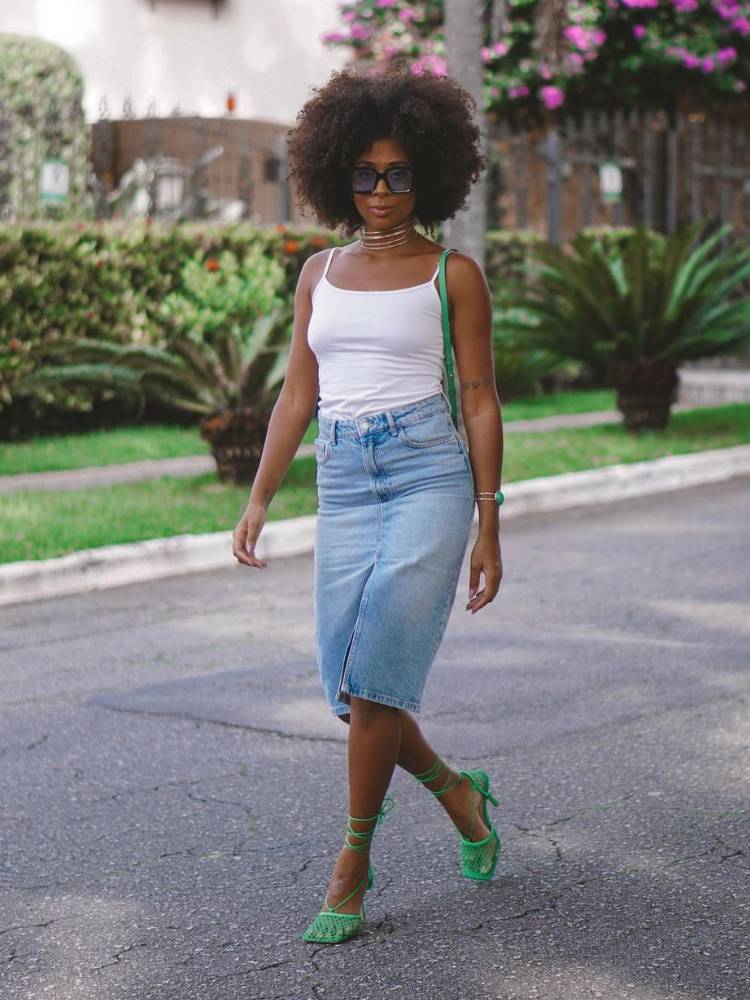 mulher usando regata branca com saia jeans mídi e sapato verde