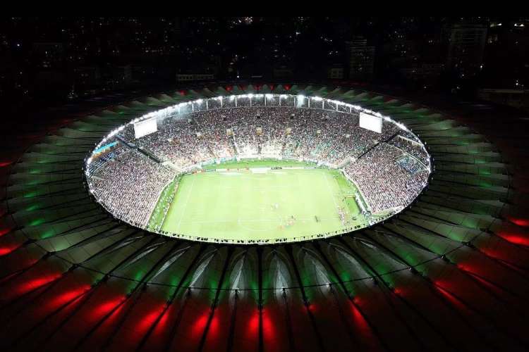 Maracanã iluminado de verde e vermelho, durante a noite. 