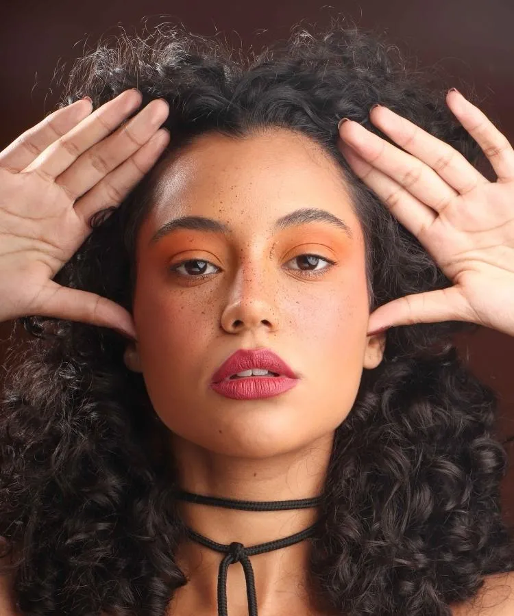 Mulher de cabelos castanhos cacheados usando maquiagem para festa junina
