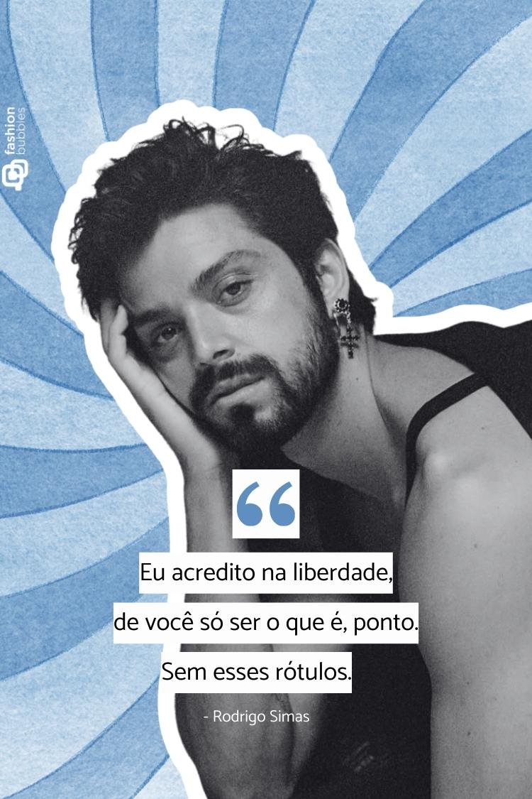 Um homem com barba e cabelo escuro, usando um brinco grande, posa casualmente com a mão na cabeça. A imagem exibe uma citação de Rodrigo Simas sobre acreditar na liberdade de ser quem se é, sem rótulos.