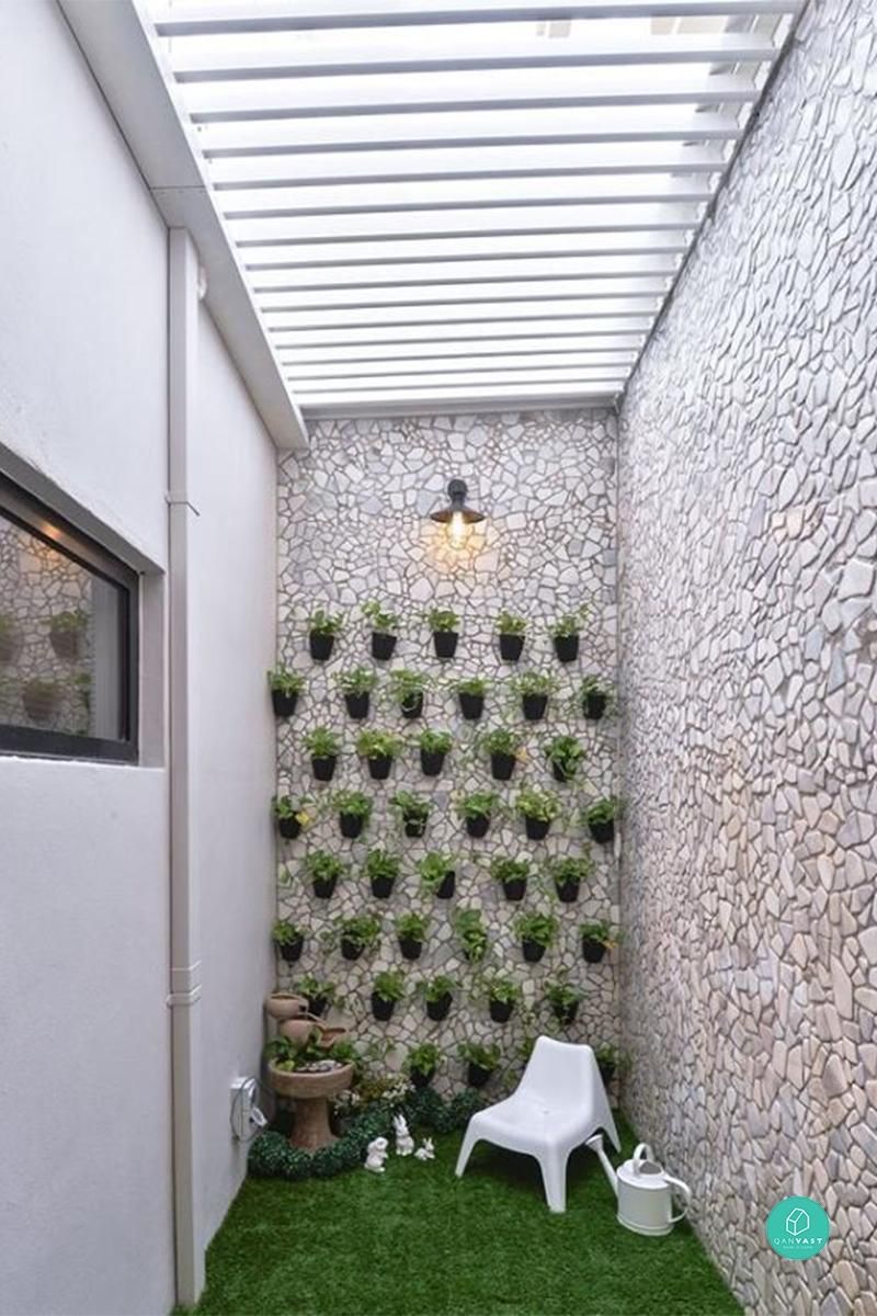 Jardim de inverno com paredes de pedra, vasos na parede, cadeira branca, fonte e regador branco