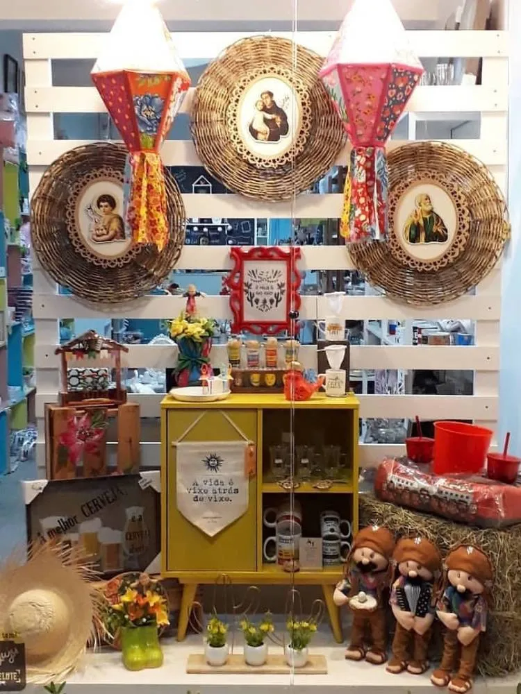 Vitrine com feno, chapéu de palha, cesto de santos, balões e mais 