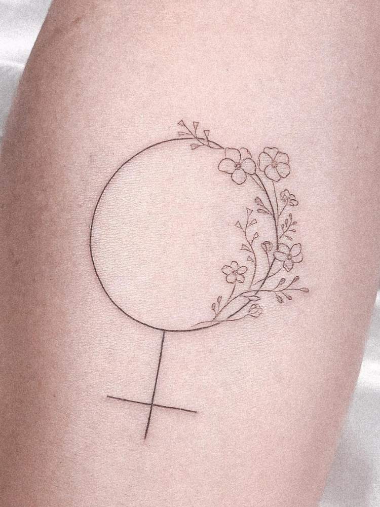 Braço com símbolo feminino tatuado com flores 