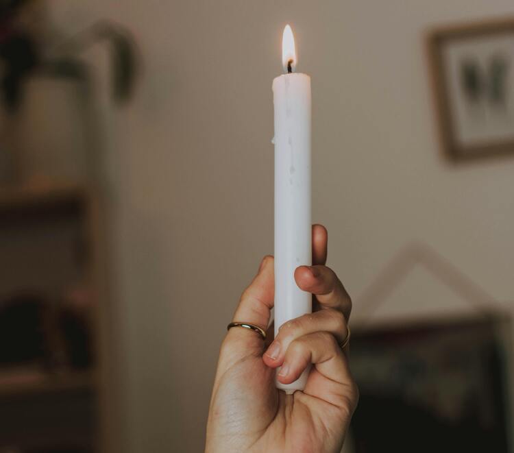 Mãos femininas segurando uma vela branca