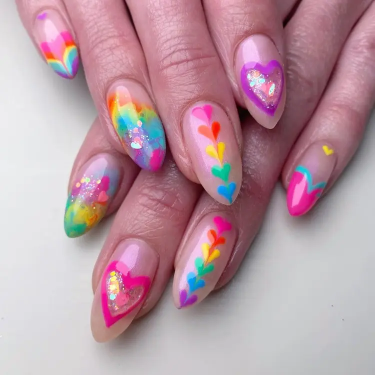 Mãos com unhas de base nude, decoração de fileira de corações coloridos, desenhos abstratos e mais 