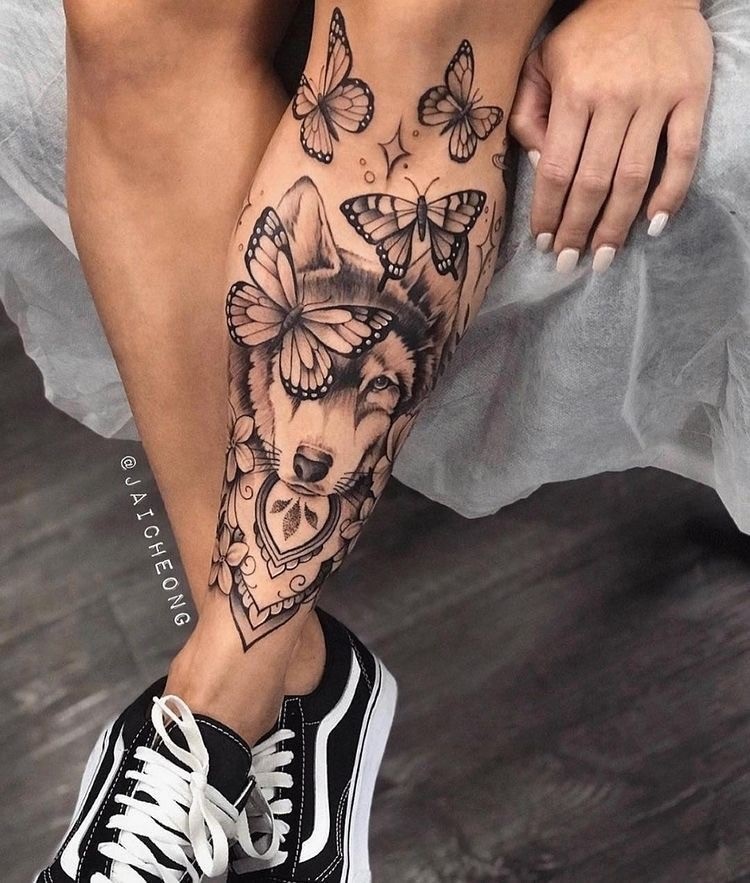 Tatuagem de lobo com borboletas na perna 