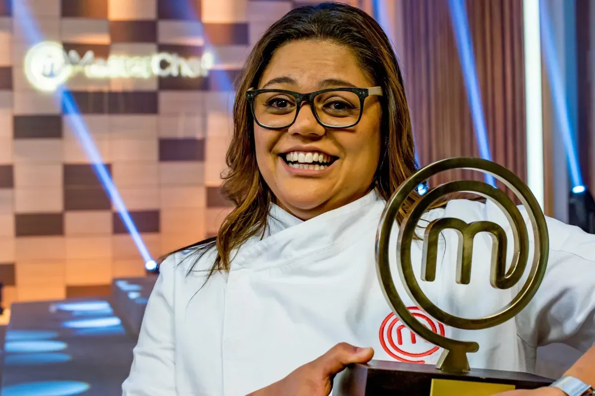 Campeã do MasterChef Brasil sorrindo ao lado do troféu durante final do reality culinário brasileiro.