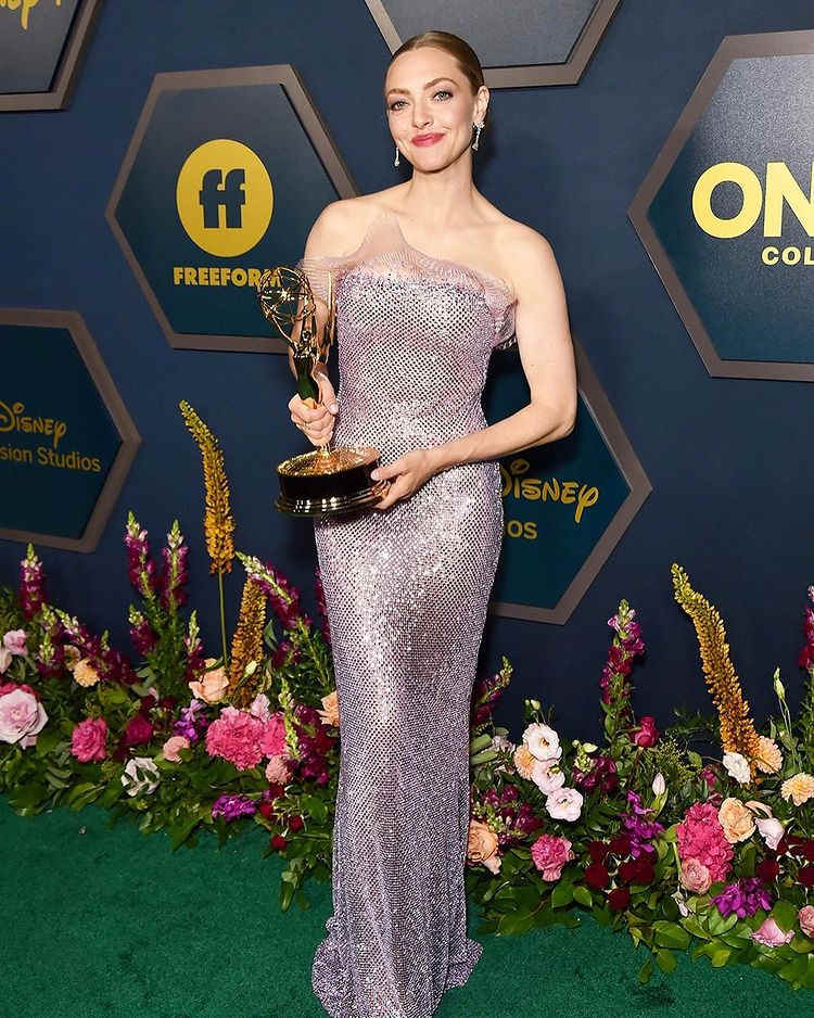 Amanda Seyfried com vestido roxo brilhoso segurando um Emmy