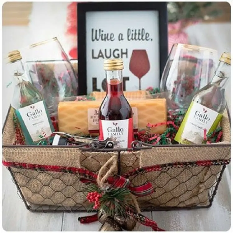 cesta de natal com garrafinhas de vinho, taças, abridor de vinho e petiscos 