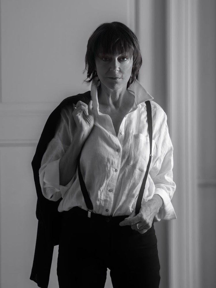 Foto de Josee Koning em preto e branco usando camisa, suspensório e calça 