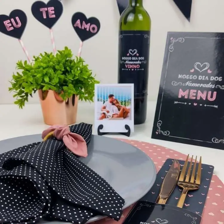 Mesa posta com guardanapo de bolinha branco e preto, foto do casal, planta e mais
