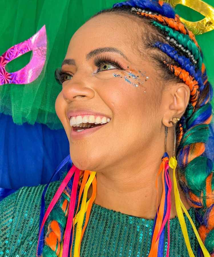 Mulher de pele negra com dread colorido e glitter colorido no rosto 