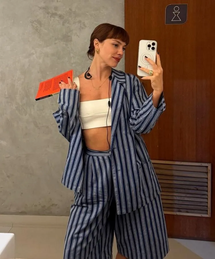 Foto de Alice Wegmann em cena usando um dos looks da Solange Duprat em Vale Tudo, conjunto de blazer e bermuda listrado azul