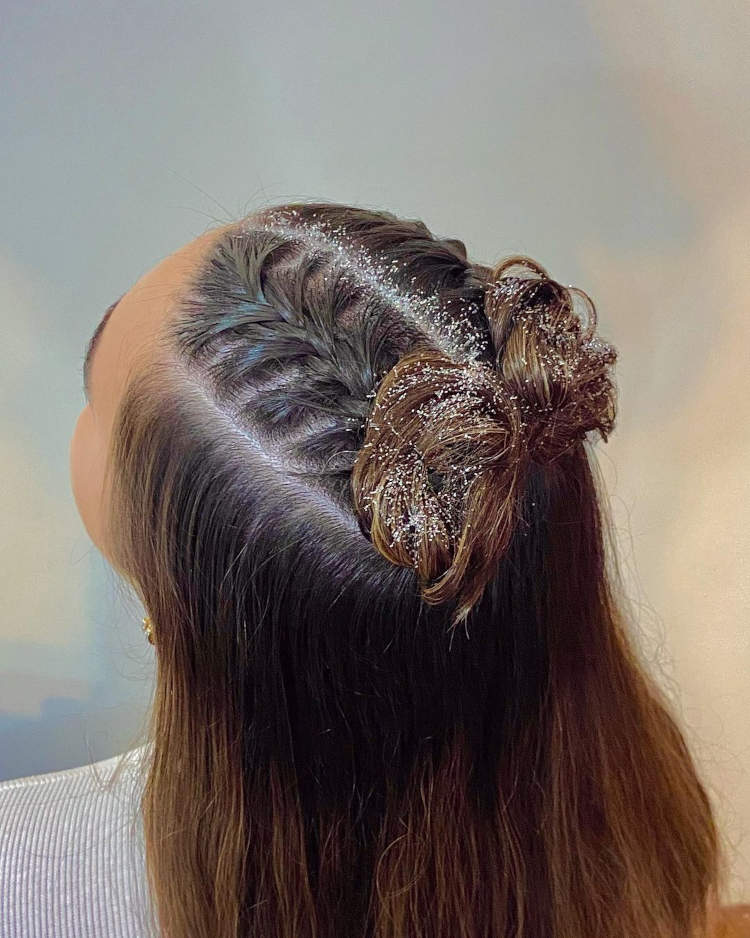 duas tranças embutidas finalizadas em um coque em cabelo castanho com glitter