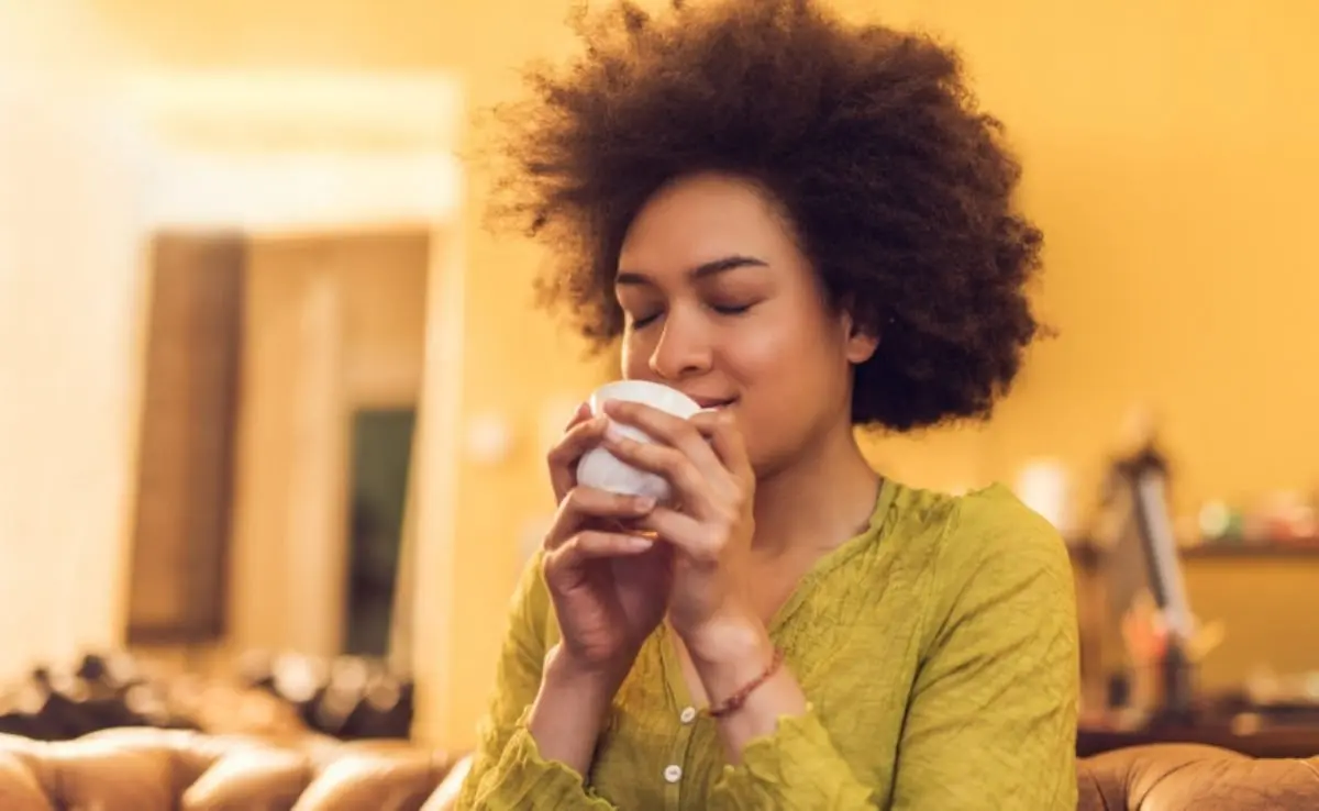 Mulher com os olhos fechados de satisfação tomando chá