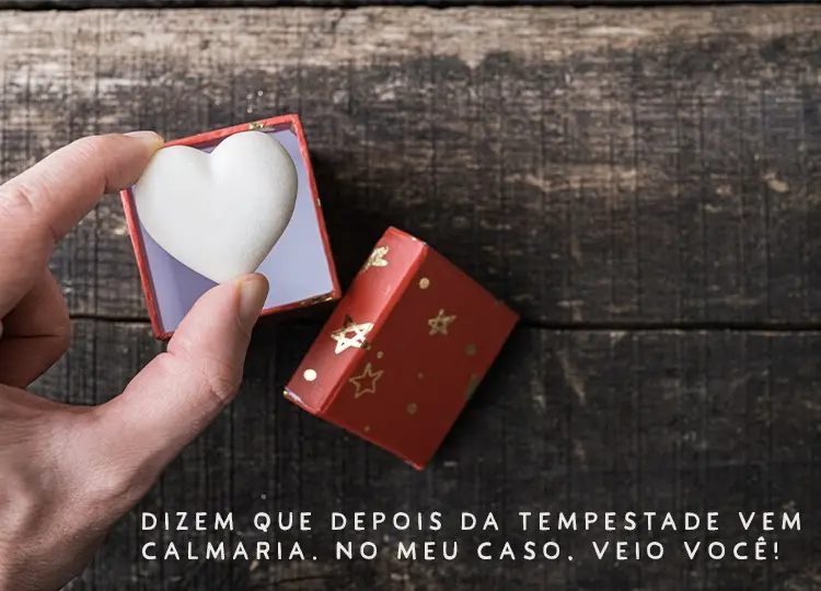 Pessoa de pele clara segurando coração branco de dentro de caixa vermelha e frase "Dizem que depois da tempestade vem a calmaria. No meu caso, veio você!"