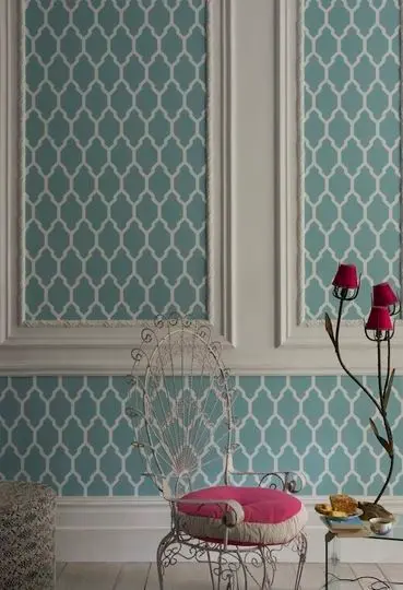 Zoom em cadeira de almofada rosa, com parede branca atrás, com moldura branca e papel de parede azul dentro 
