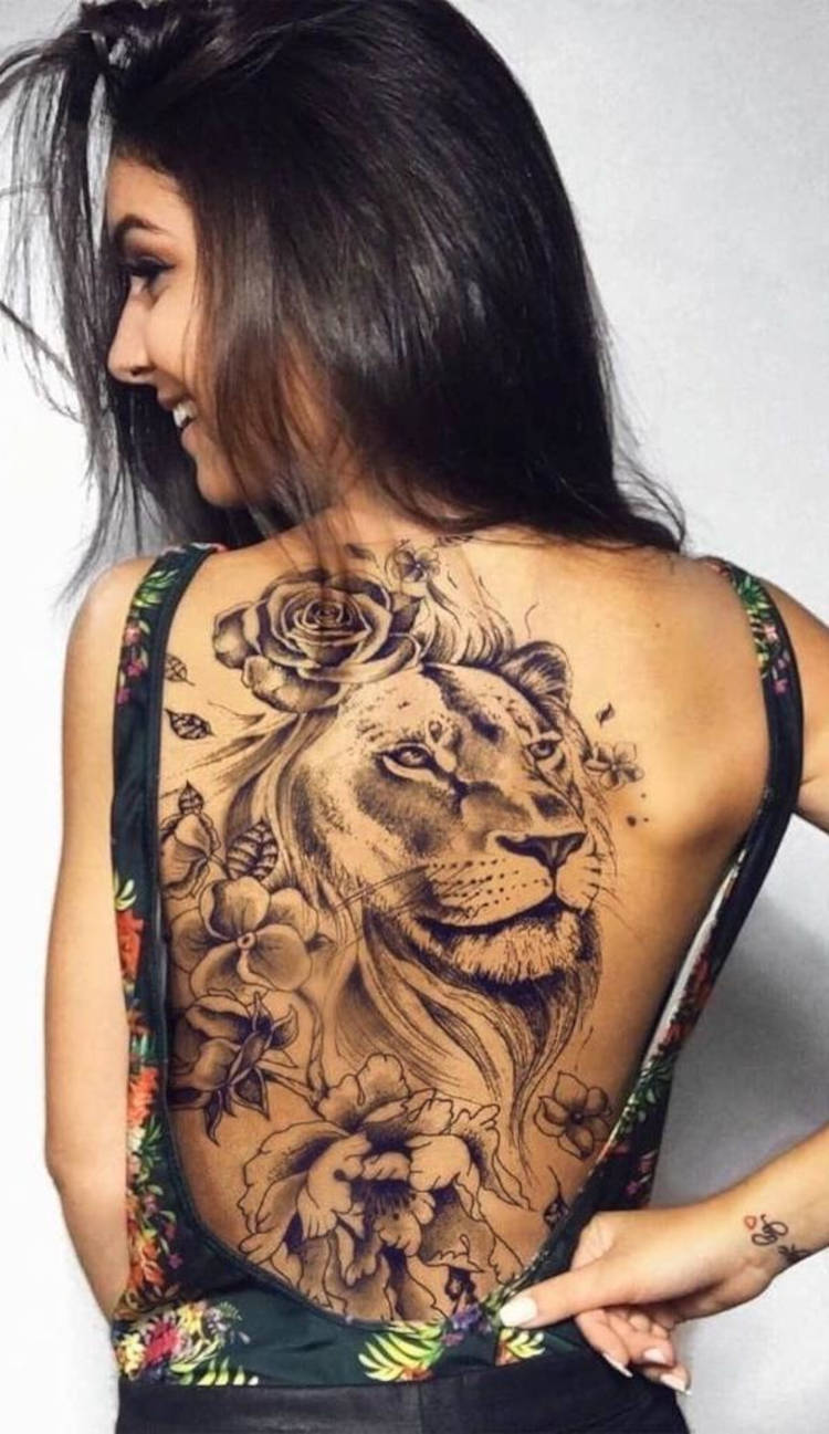 Mulher de pele clara com tatuagem de leão grande com flores nas costas