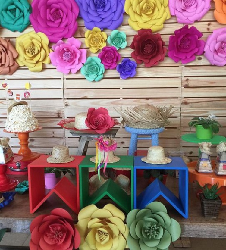 A imagem representa painel de pallet em decoração de festa caipira e flores de papel
