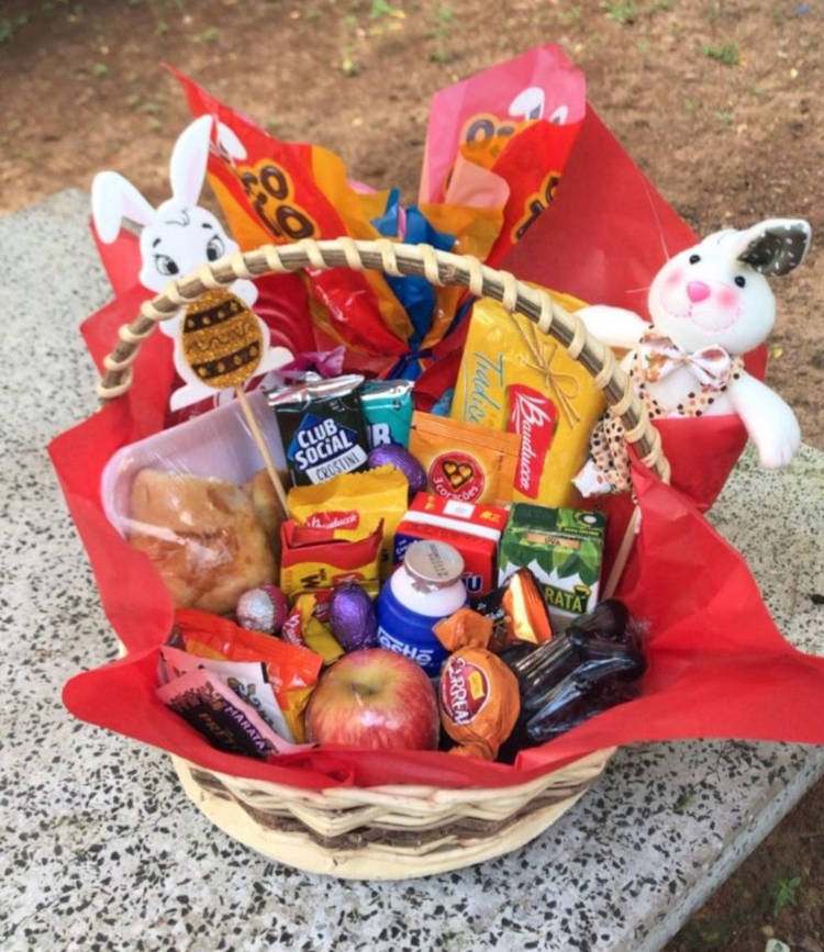 cesta de páscoa com guloseimas, maçã e coelho de pelúcia.