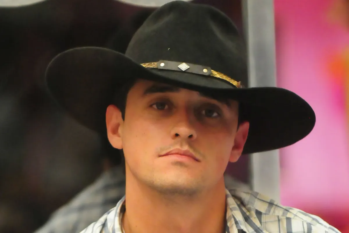 Homem com chapéu preto estilo country e camisa xadrez em programa de televisão