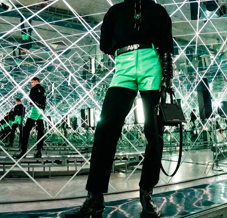 Modelo de roupa preta e short verde vivo por cima.