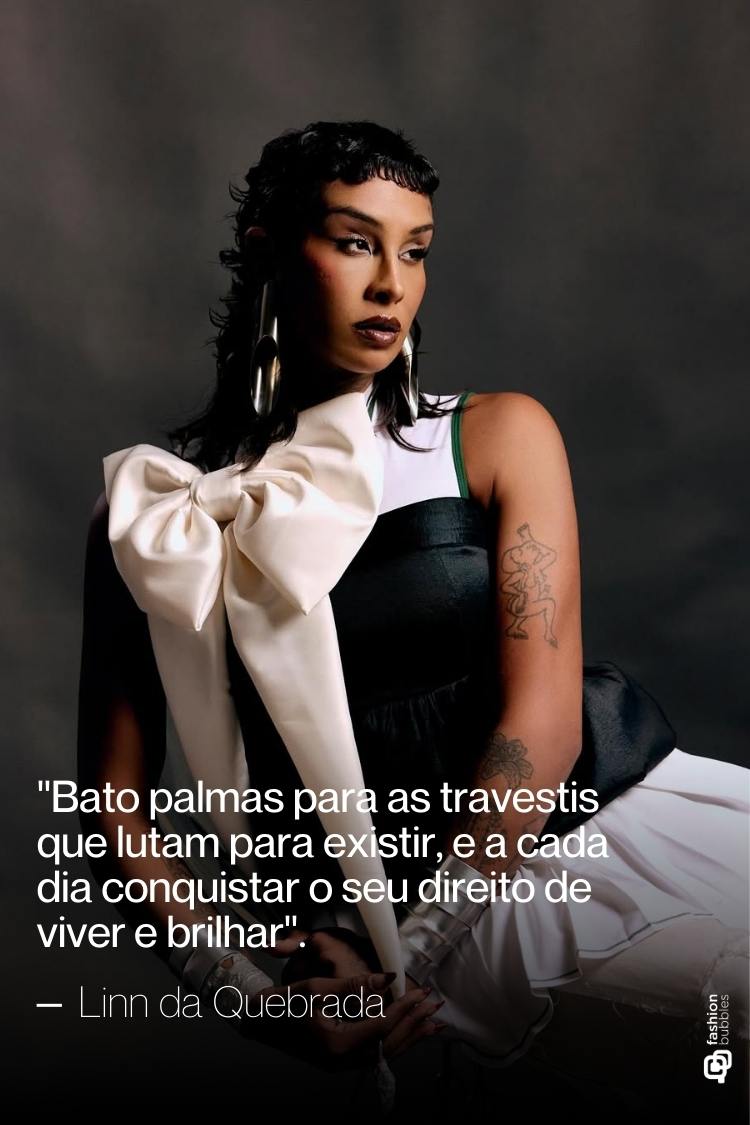 Uma pessoa com cabelo escuro e maquiagem marcante usa um top preto com um grande laço creme, e tem tatuagens visíveis no braço esquerdo. A imagem inclui uma citação atribuída a Linn da Quebrada sobre travestis lutando para existir.
