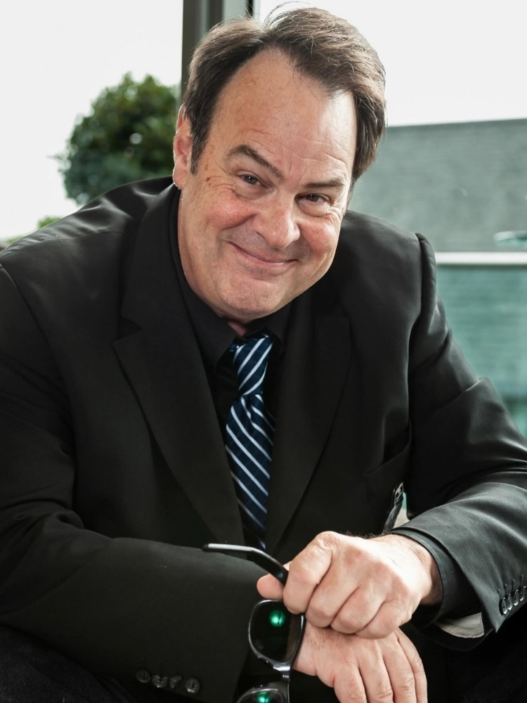 Dan Aykroyd de terno, sentado