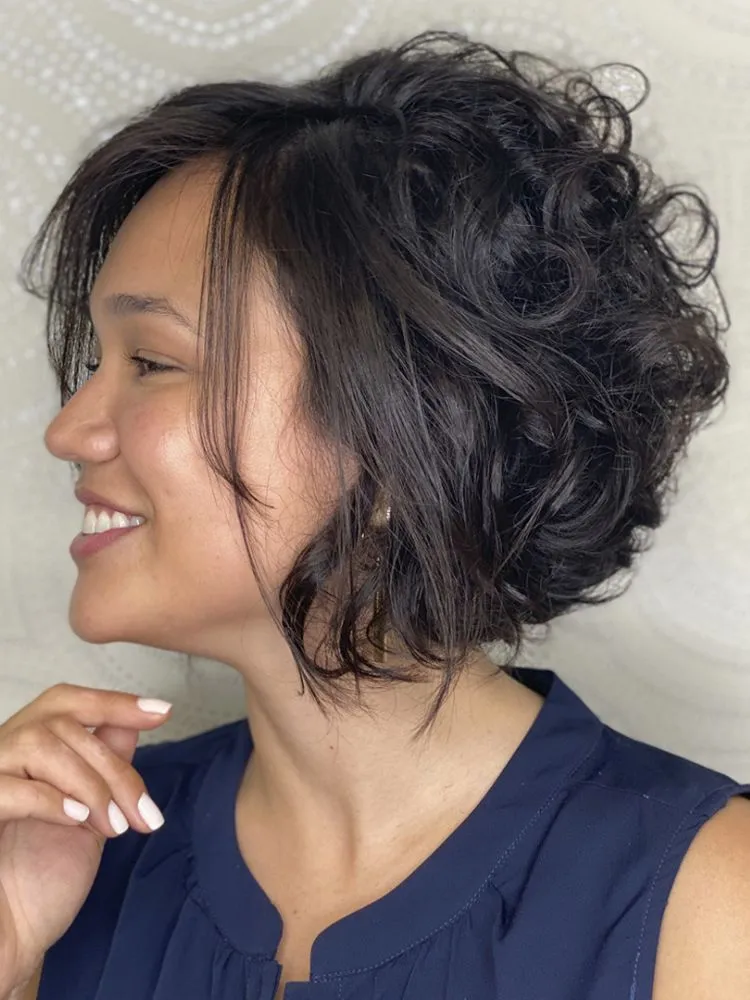 Mulher de perfil com cabelo curto repicado, liso na frente e cacheado atrás