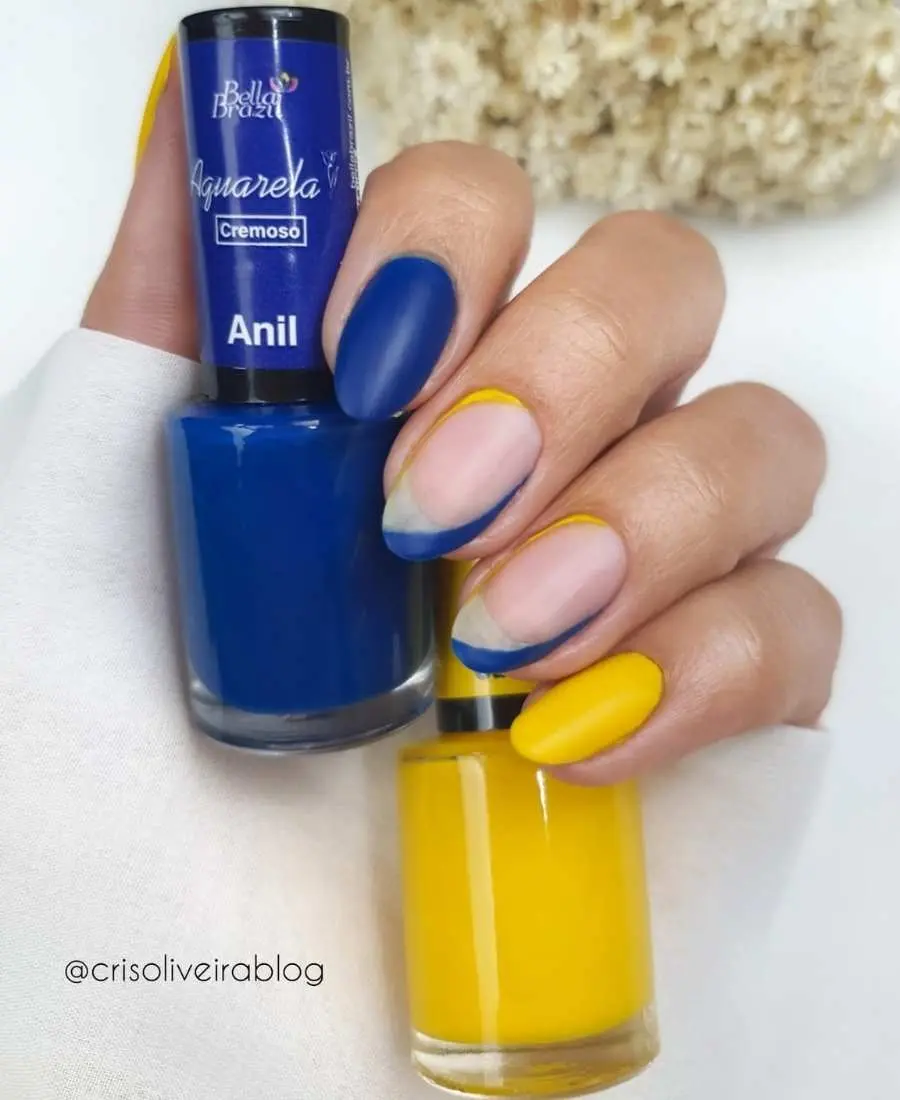 Imagem de mão com unhas decoradas para a Copa do Mundo 2022. Cores usadas: azul e amarelo. Polegar, amarelo. Indicador, azul. Médio amarelo e azul. Anelar, amarelo e azul. Mínino, amarelo.