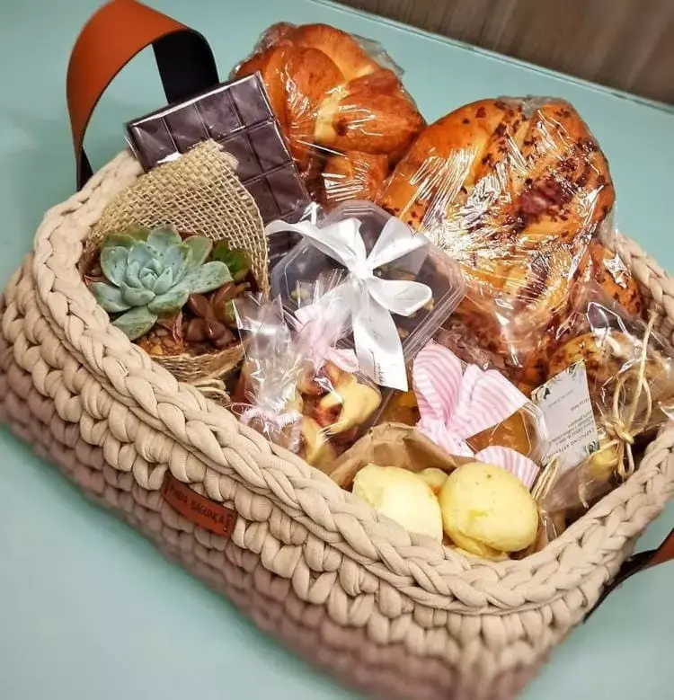 Cesta de fio de malha com pães e doces artesanais, além de suculenta 