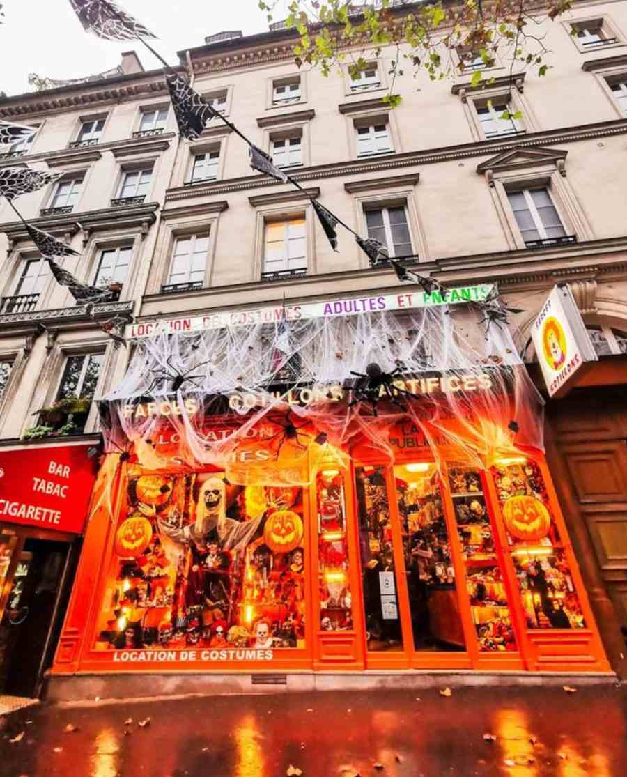 Foto de uma vitrine de Halloween laranja com teias de aranha e aranhas na fachada