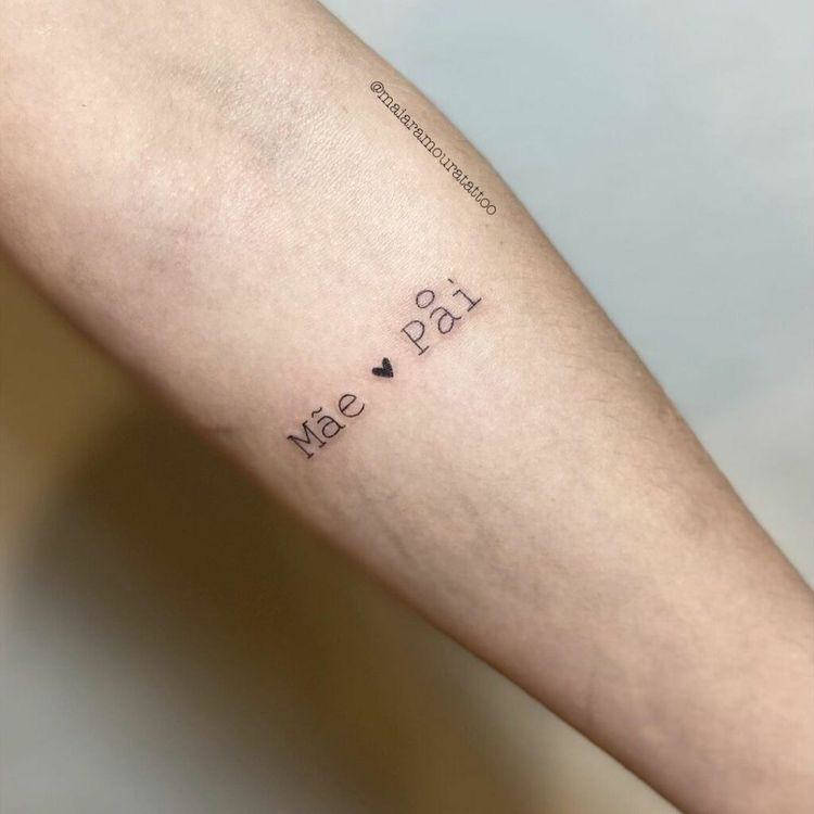 Braço de pele clara escrito "mãe" e "pai" com um coração no meio 