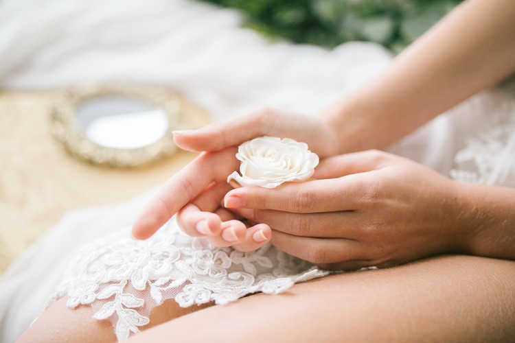 mãos femininas segurando uma rosa branca