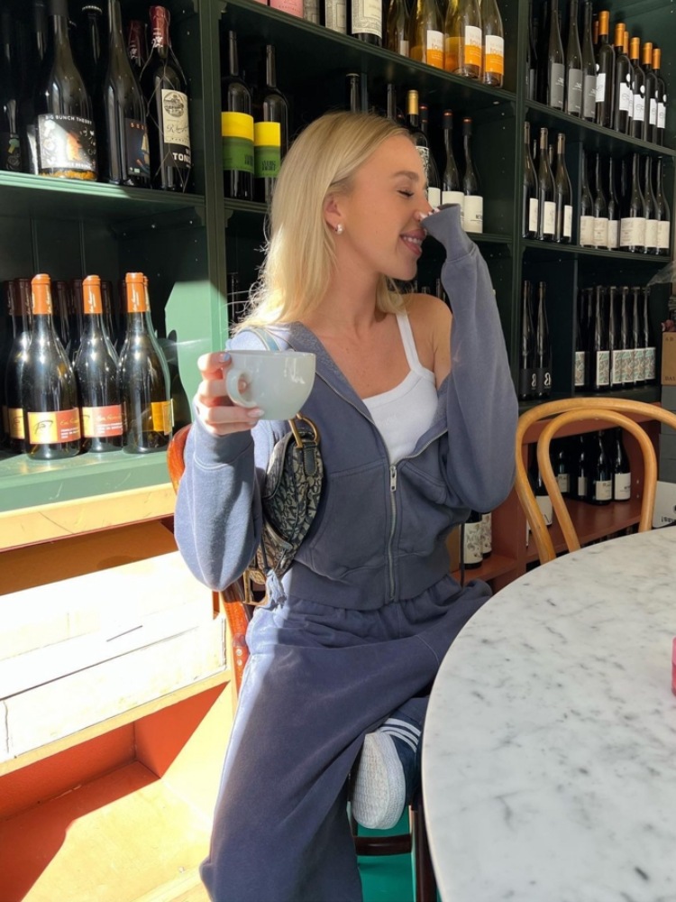 mulher usando conjunto de moletom monocromático cinza com regata branca por baixo e bolsa dior estilo baguette