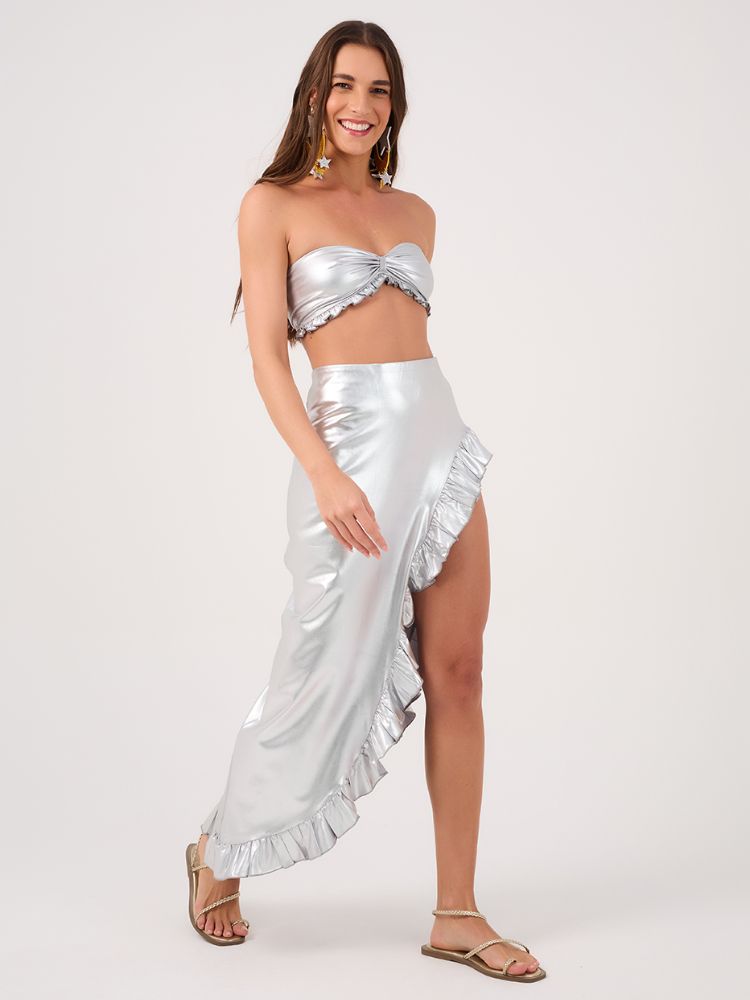 Mulher de pele clara usando top prata e saia midi prata com fenda 