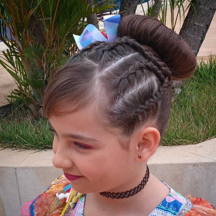 Menina de cabelo castanho escuro com tranças e coque alto.