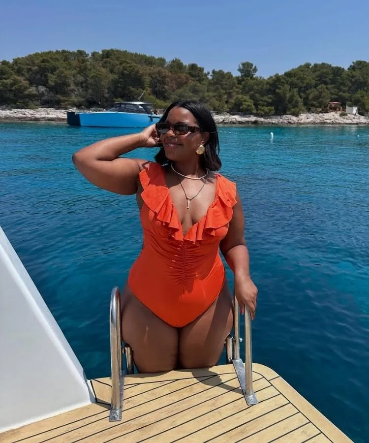 Foto de mulher com maiô laranja com detalhe de babados, uma das tendências da moda praia 2026