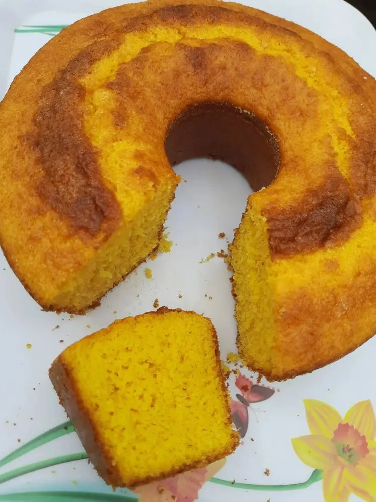 Bolo redondo de milho com furo e uma fatia cortada 