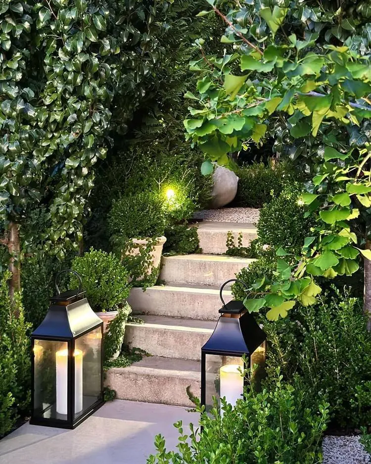 Escada com vasos de plantas, luminárias e outras plantas verdes ao redor.