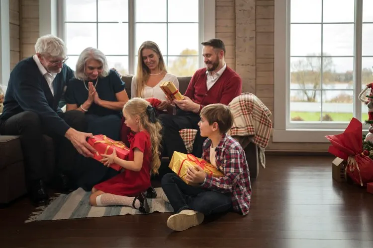 Família com pais, avós e netos trocando presentes no Natal.