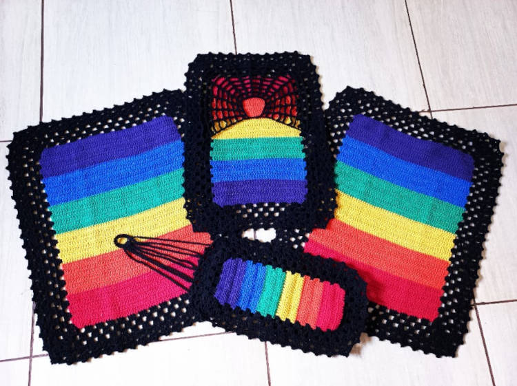 Tapete de crochê com as cores do bandeira LGBTQIA+ e borda preta.