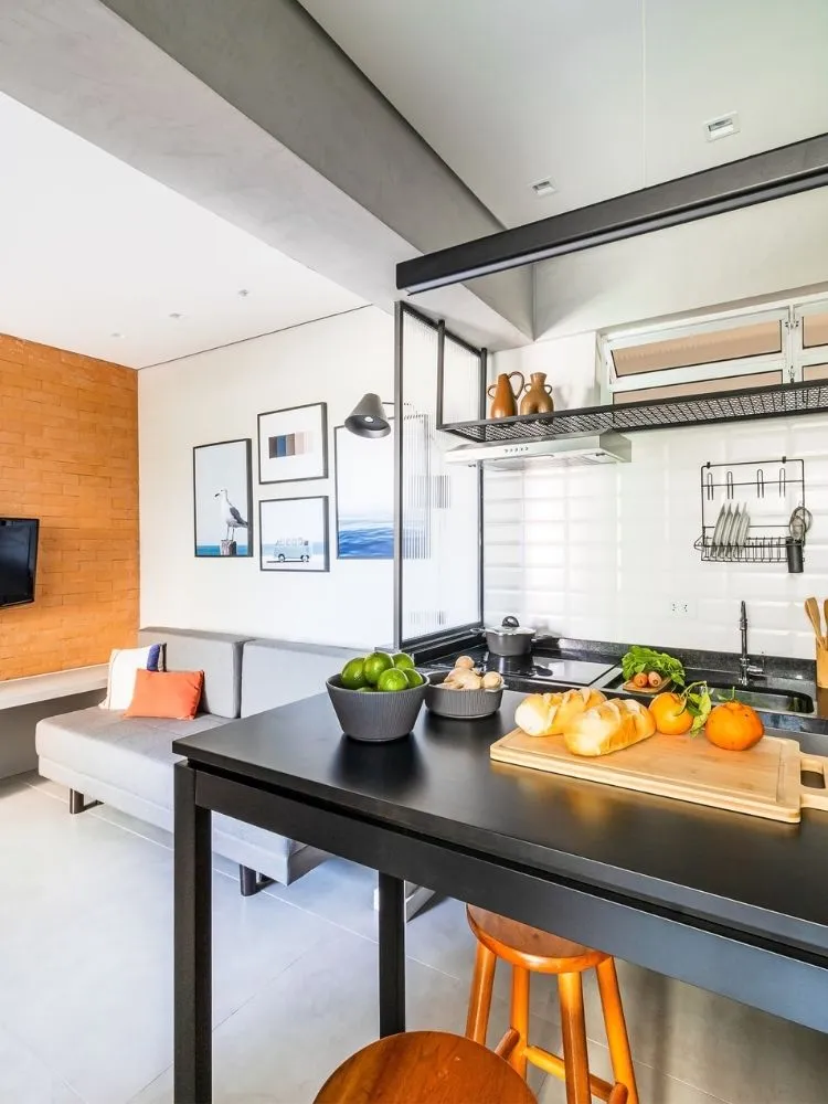 Cozinha integrada com sala, onde há uma parede de tijolinhos à mostra