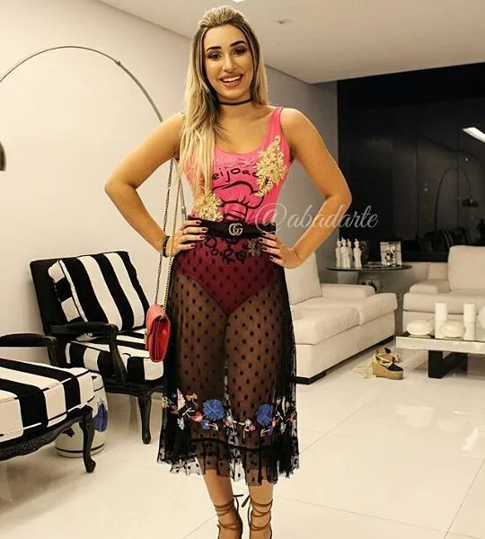 Foto de mulher de pele clara com abadá rosa emm body  e saia transparente preta