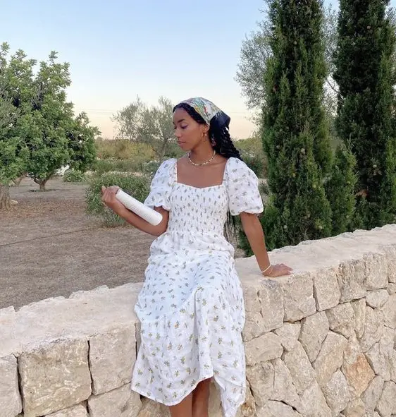 Vestido Cottagecore, modelo sentada em muro lendo