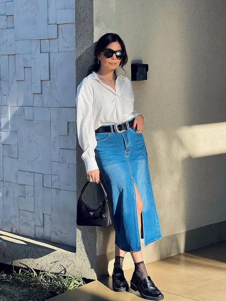 mulher usando camisa branca, saia mídi jeans e mocassim preto com meia de strass preta