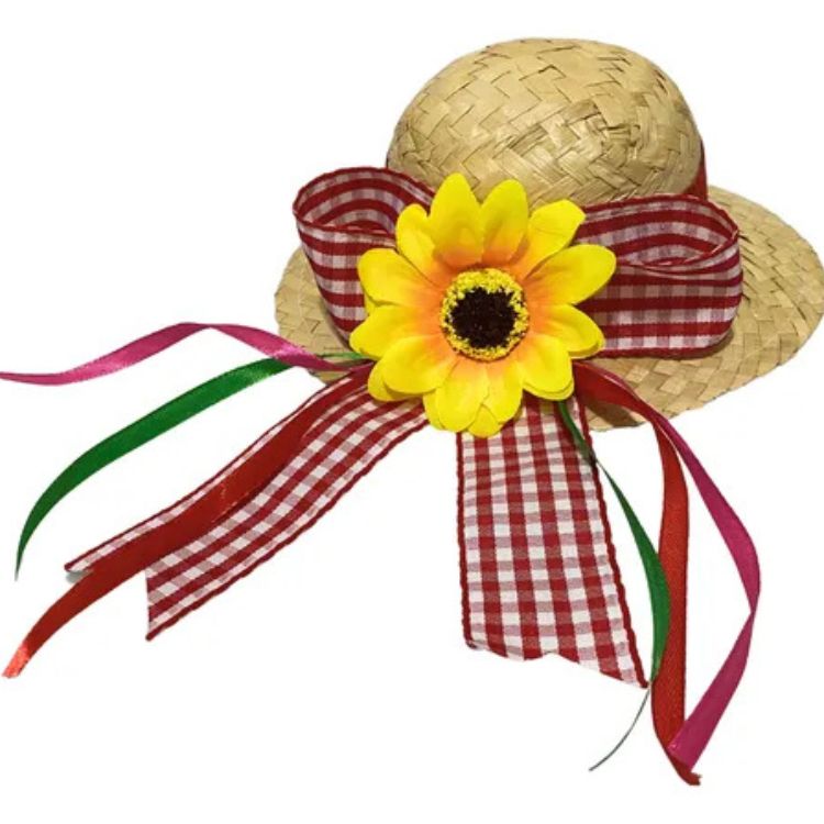 Um chapéu de festa junina de palha em miniatura decorado com uma fita xadrez vermelha e branca, um girassol amarelo brilhante e fitas multicoloridas que caem em cascata.